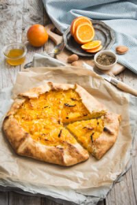 Oranges fraîches entassées avec des feuilles vertes sur fond de bois rustique
