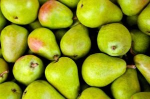 Poire mûre sur une table en bois avec feuilles d'automne en arrière-plan